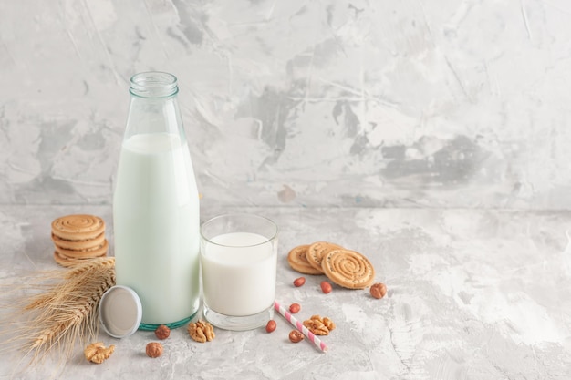 Vue de face d'une bouteille en verre remplie de bouchon de lait et de biscuits pointes de bonbons aux cacahuètes et aux noix sur fond blanc teinté