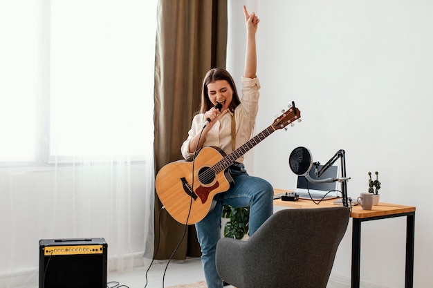 Vue de face de la chanteuse musicienne et enregistrement de la chanson avec guitare acoustique