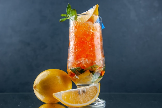 vue de face cocktail orange frais avec du citron et de la glace sur fond bleu clair boisson froide limonade jus de barre de glace