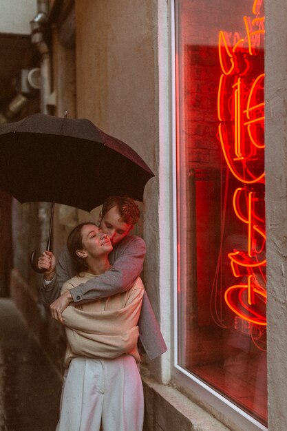 Photo vue de face couple romantique avec parapluie