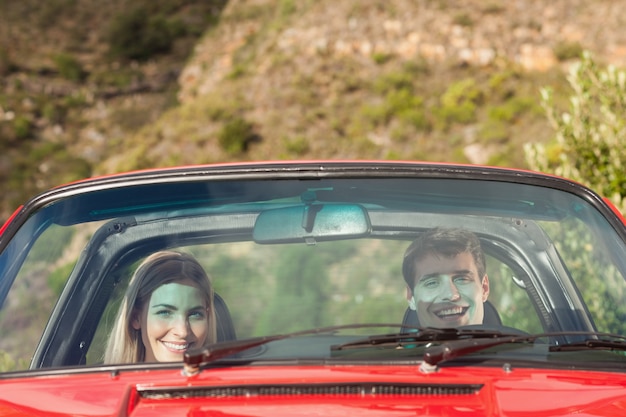 Vue de face d&#39;un couple souriant en cabriolet rouge