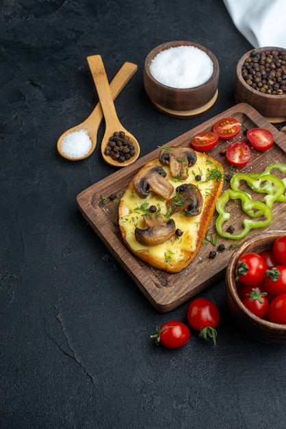 Vue de face d'une délicieuse collation avec des champignons et des légumes hachés sur des couverts en bois mis des épices sur fond noir