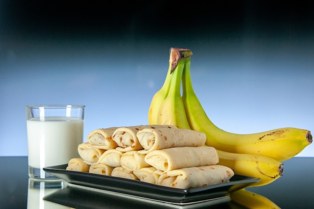 vue de face de délicieuses crêpes roulées avec des bananes et du lait sur fond clair fruit matin sucré gâteau au lait dessert au lait