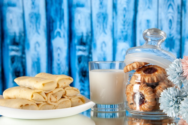 vue de face de délicieux crêpes avec du lait et des biscuits sur un fond bleu clair dessert couleur cookie petit déjeuner sucré repas sucre gâteau matin