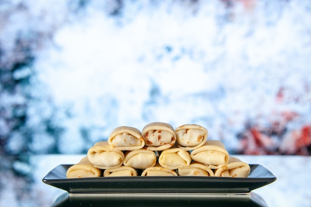 vue de face de délicieux crêpes roulées à l'intérieur de la plaque sur le fond clair fleur du matin petit-déjeuner au lait gâteau de couleur douce dessert au sucre