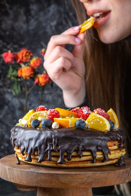 Vue de face délicieux gâteau au chocolat avec des fruits frais sur un mur sombre