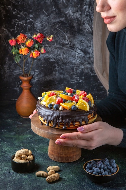 Vue de face délicieux gâteau au chocolat avec des fruits frais sur un mur sombre