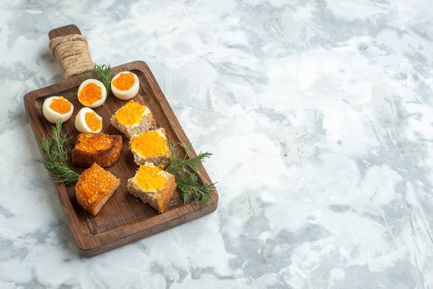 vue de face délicieux sandwichs au caviar et œufs durs sur une planche à découper surface blanche déjeuner nourriture petit déjeuner poisson fruits de mer repas horizontal