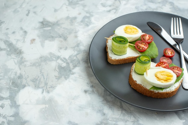 vue de face délicieux sandwichs aux œufs avec couteau et fourchette à l'intérieur de la plaque surface blanche sandwich régime déjeuner pain toast nourriture repas santé burger