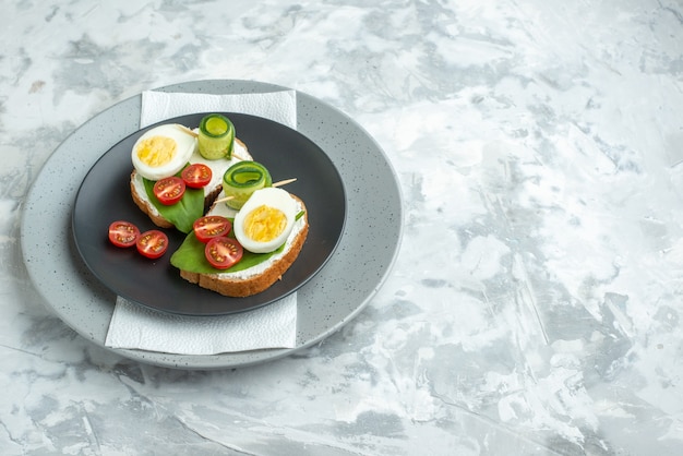 Vue de face de délicieux sandwichs aux œufs à l'intérieur de la plaque sur fond blanc sandwich burger régime alimentaire repas pain santé déjeuner