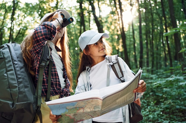 Vue de face Deux filles sont dans la forêt ayant une activité de loisir à la découverte de nouveaux endroits