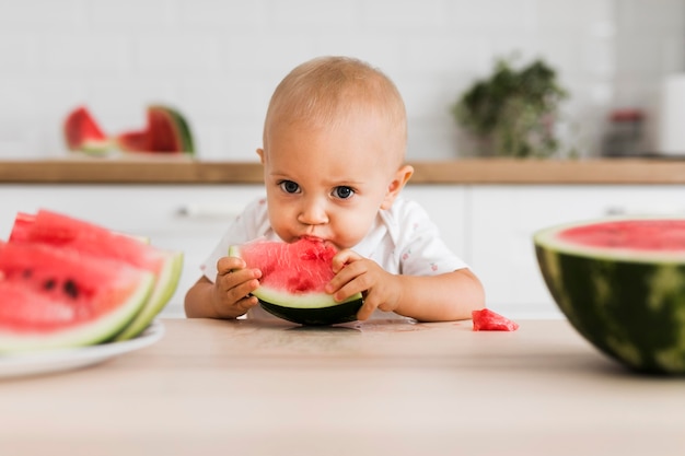 Photo vue de face du beau bébé mangeant de la pastèque