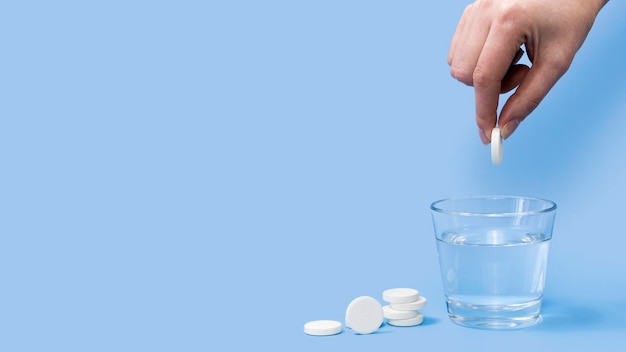 Vue De Face Du Comprimé Effervescent Tombant à La Main Dans Un Verre D'eau Avec Copie Espace