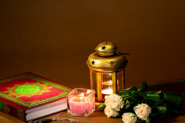 Vue de face du Coran avec des bougies et des roses