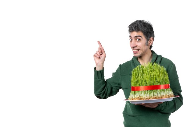 vue de face du jeune homme tenant un grand novruz semeni traditionnel sur un mur blanc