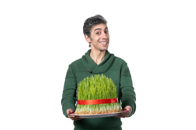 vue de face du jeune homme tenant un grand novruz semeni traditionnel sur un mur blanc