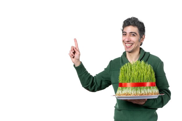 vue de face du jeune homme tenant un gros novruz semeni attaché avec un arc rouge sur un mur blanc