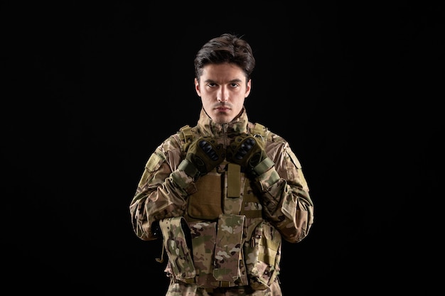 Vue de face du militaire en uniforme sur mur noir