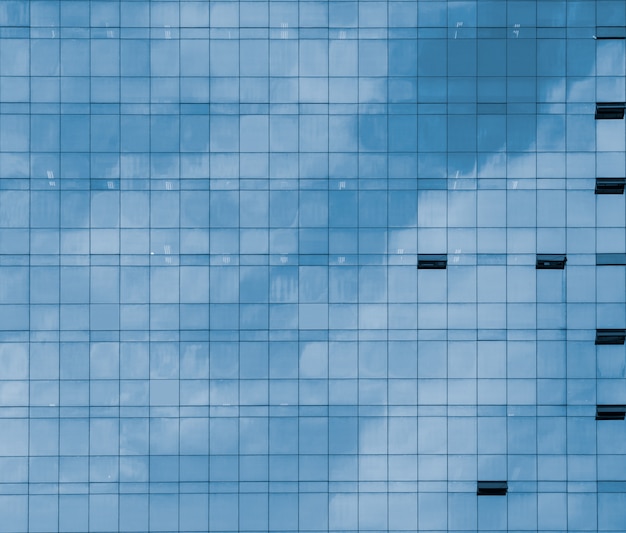 Vue de face du modèle de fenêtre en verre d'un immeuble de bureaux moderne avec des nuages et un ciel bleu reflètent