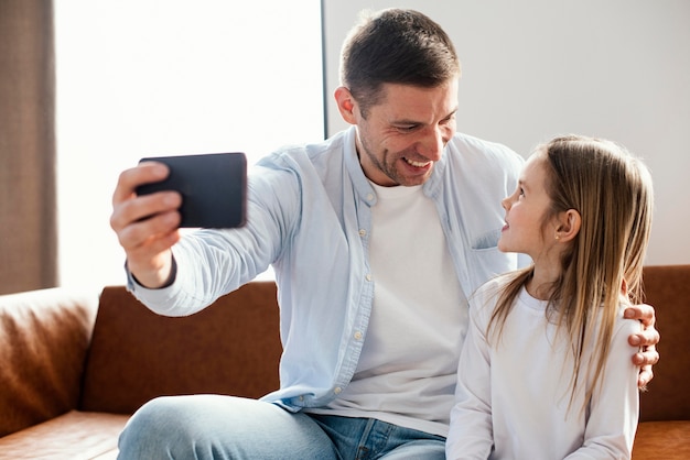 Vue de face du père souriant prenant selfie avec sa fille