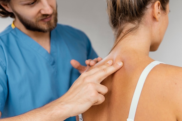 Photo vue de face du thérapeute ostéopathe masculin contrôle la colonne vertébrale du patient