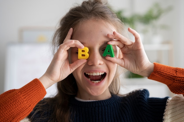 Photo vue de face enfant tenant des lettres