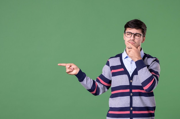 vue de face enseignant pointant de côté avec l'expression de la pensée sur fond vert collège femme leçon bibliothèque étudiant université livre couleur travail scolaire