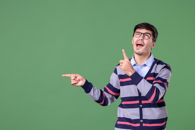 Vue de face enseignant pointant de côté avec l'expression de la pensée sur fond vert collège femme leçon bibliothèque étudiant université livre couleurs travail