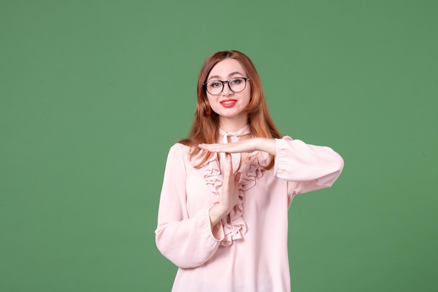 Vue de face enseignante en chemisier rose faisant t-lettre sur vert