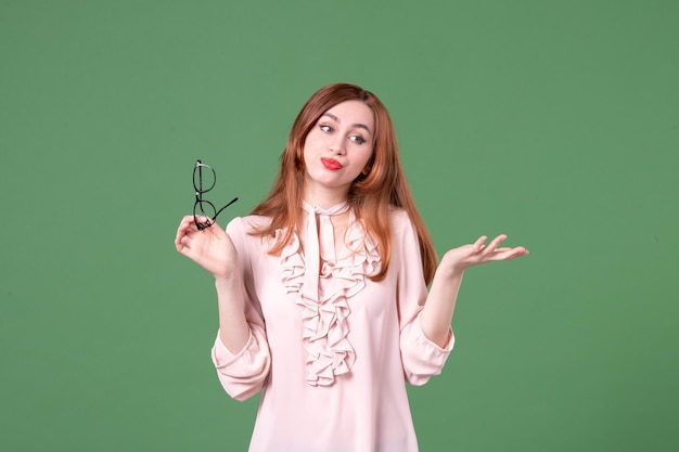 Vue de face enseignante en chemisier rose sur fond vert collège couleur livre de travail étudiant emploi femme bibliothèque leçon école