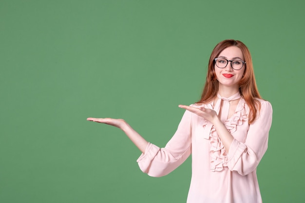 Vue de face enseignante en chemisier rose sur fond vert emploi école couleur livre jeune leçon travail femme étudiant bibliothèque collège