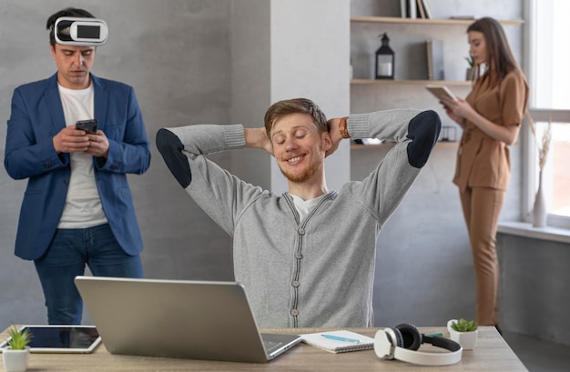 Photo vue de face de l'équipe de jeunes utilisant un ordinateur portable et un casque de réalité virtuelle