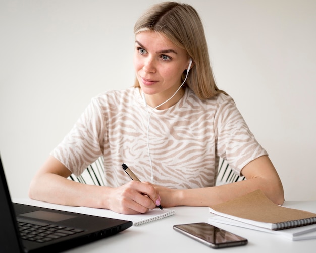 Vue de face étudiant assis à son bureau à domicile