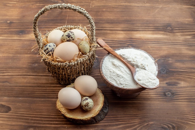 Photo vue de face farine blanche avec des œufs sur un bureau en bois marron repas tarte biscuit four gâteau cuisson cuisson