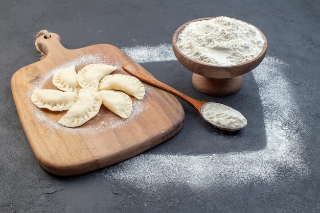 vue de face farine blanche avec petits petits pains crus sur fond sombre pâte four gâteau tarte biscuit cuire la poussière de cuisson