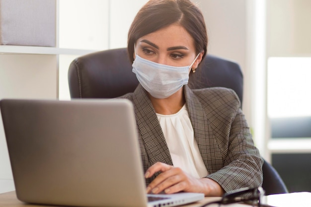 Photo vue de face de la femme d'affaires avec masque facial travaillant au bureau