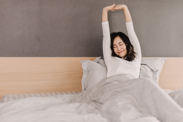 Vue de face d'une femme asiatique au matin. elle s'étire la main et le corps avec un beau sourire