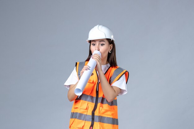 Vue De Face D'une Femme Builder En Uniforme Avec Une Affiche Dans Ses Mains Sur Un Mur Blanc