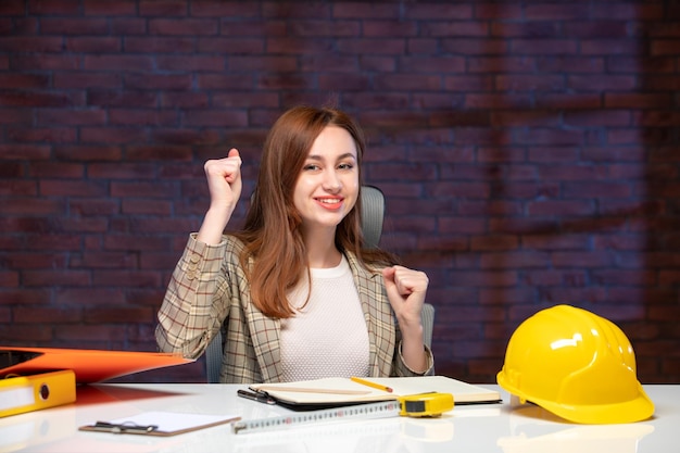 vue de face femme ingénieur assis derrière son lieu de travail dans le chantier de construction programme d'emploi constructeur entrepreneur succès d'entreprise plan d'entreprise