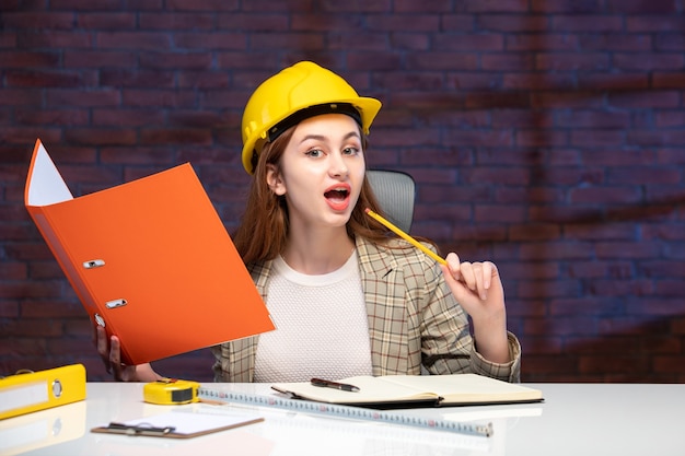 vue de face femme ingénieur assis derrière son lieu de travail travaillant avec des documents travail succès d'entreprise agenda d'affaires entrepreneur constructeur de propriétés