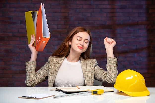 vue de face femme ingénieur assise derrière son lieu de travail avec des documents agenda du constructeur d'emplois plan d'affaires succès entrepreneur immobilier