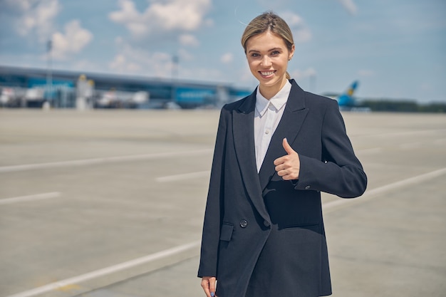 Vue de face d'une femme joyeuse dans une veste à la mode montrant un geste d'approbation