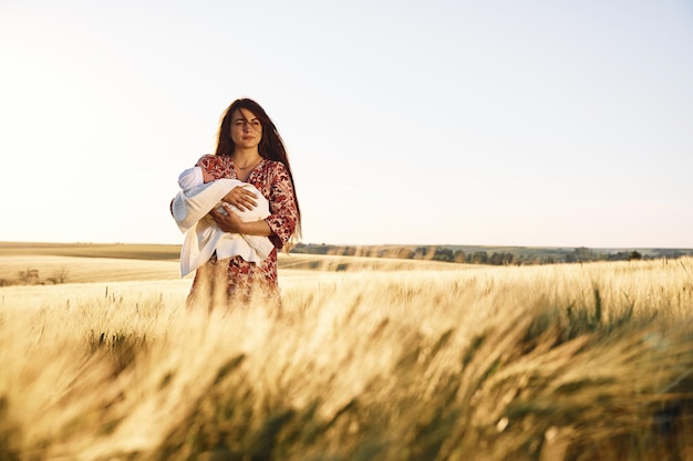 Vue de face Une femme magnifique est sur le terrain agricole avec son nouveau-né