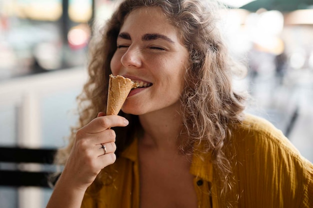 Photo vue de face d'une femme mangeant un cornet de crème glacée