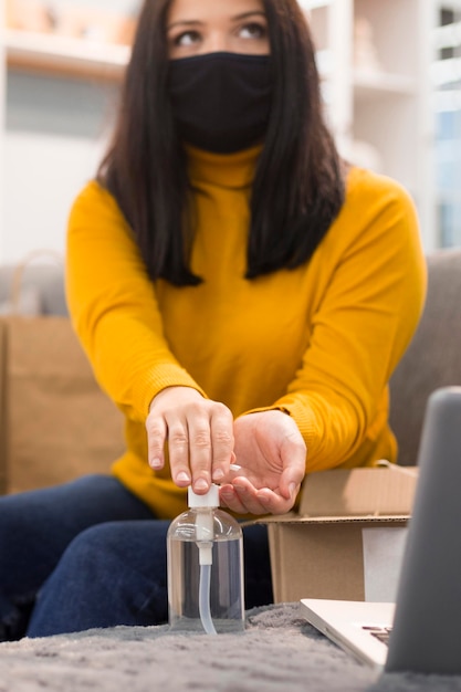 Photo vue de face femme avec masque médical désinfectant ses mains