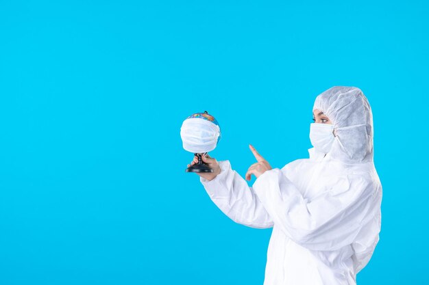 vue de face femme médecin en tenue de protection et masque tenant un globe masqué sur fond bleu virus covid- pandémique science des couleurs médicales