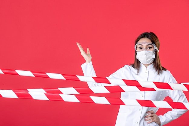 Photo vue de face femme médecin en uniforme médical et masque sur fond rouge ligne de crime scellée virus covid- hôpital médical