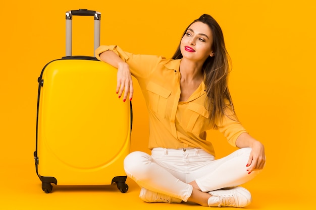 Vue de face de femme posant joyeusement à côté de ses bagages