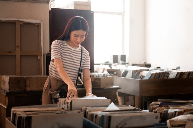 Photo vue de face femme regardant des disques vinyles