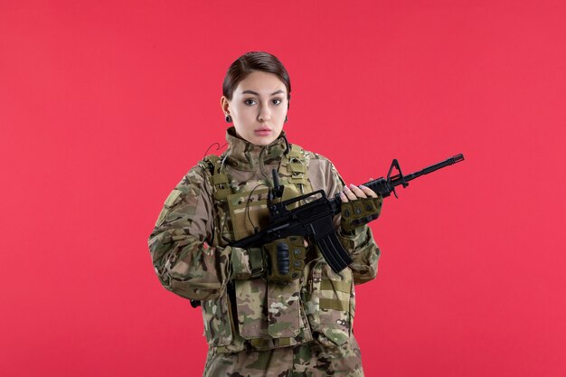 Vue de face femme soldat en uniforme militaire avec mur rouge de mitrailleuse